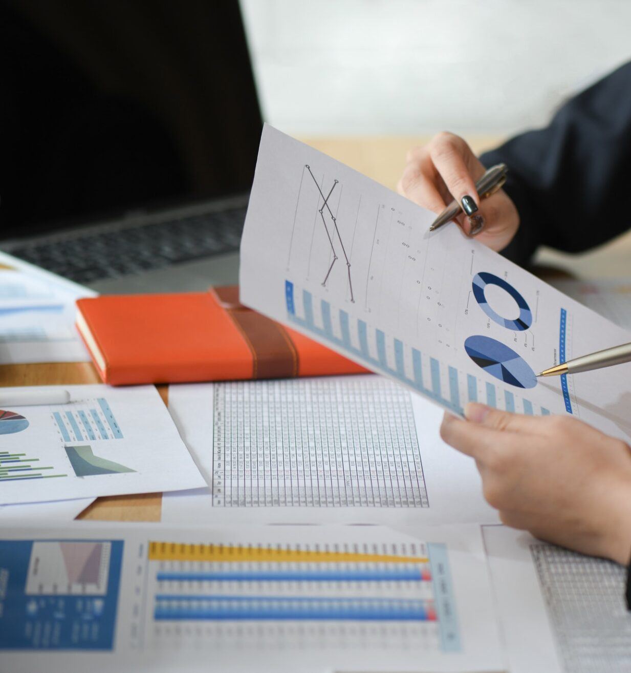Zwei Mitarbeiterinnen analysieren Diagramme und Daten auf Papier