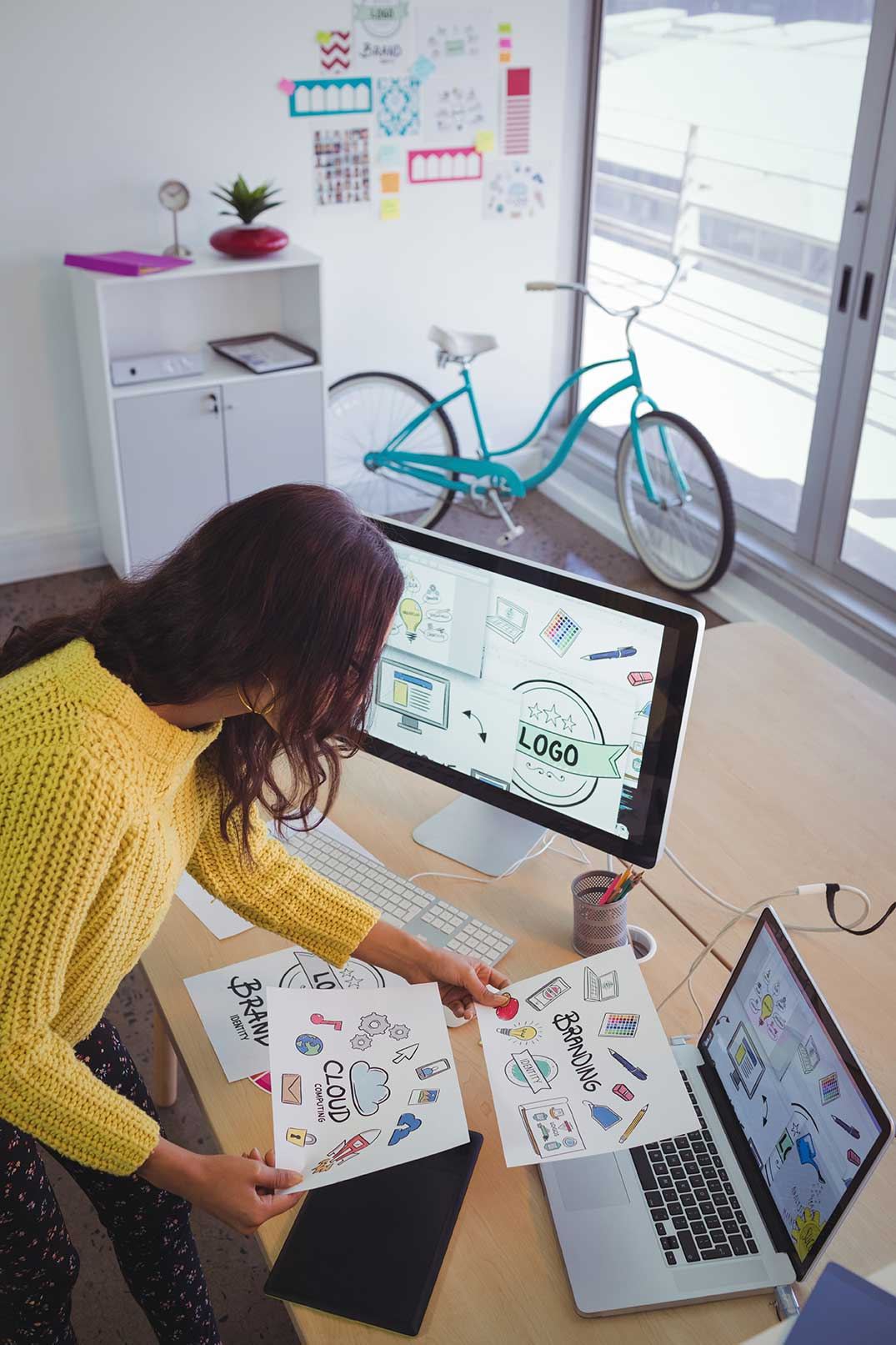 Grafikdesignerin arbeitet an Entwürfen am Schreibtisch mit Bildschirm