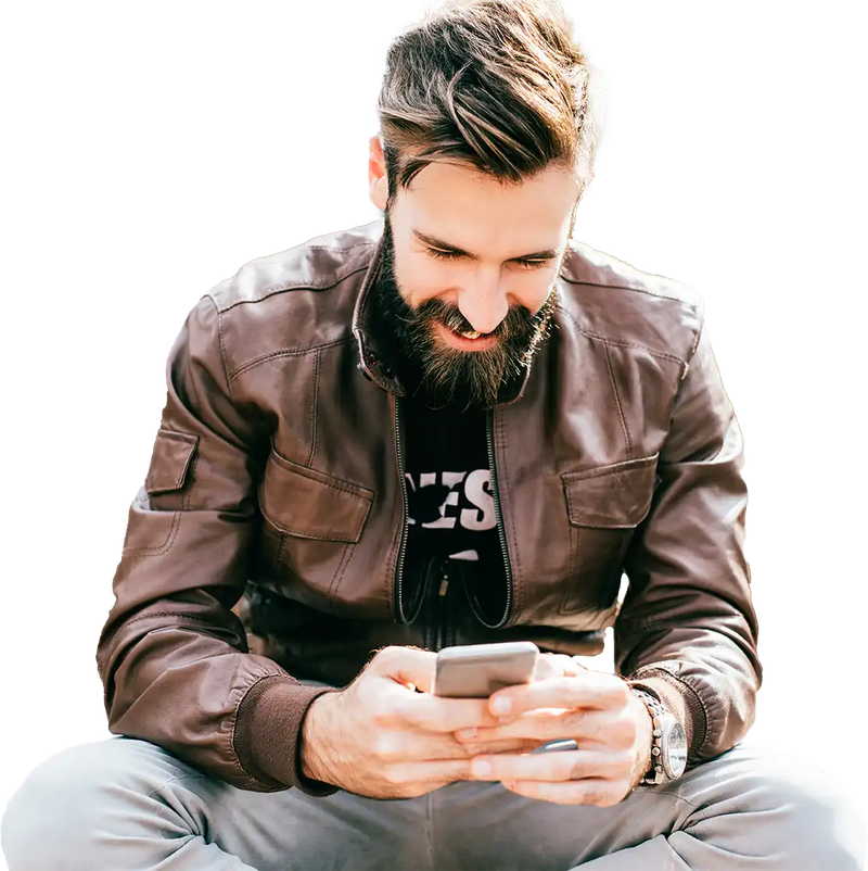 Mann mit Bart sitzt entspannt da und scrollt lächelnd auf seinem Smartphone